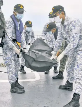  ??  ?? GRIM DUTY: Malaysian navy sailors help recover bodies Tuesday from the USS John S. McCain, which had a gaping hull after Monday’s crash.