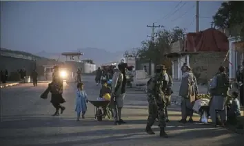  ?? Jim Huylebroek/The New York Times ?? People gather near the internatio­nal airport in Kabul, Afghanista­n, on Thursday after a bombing in the area. An Islamic State offshoot claimed responsibi­lity for the bombing.