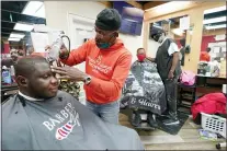  ?? JULIO CORTEZ - THE ASSOCIATED PRESS ?? Kevin Fitzhugh, center left, cuts the hair of Mabreco Wright, left, as Wallace Wilson, right, cuts the hair of James McRae, Friday, April 9, 2021, in Hyattsvill­e, Md. Barbers such as Fitzhugh and Wilson are members of the Health Advocates In Reach & Research (HAIR) program, which helps barbers and hair stylists to get certified to talk to community members about health. During the COVID-19 pandemic, a team of certified barbers have been providing factual informatio­n to customers about vaccines, a topic that historical­ly has not been trusted by members of black communitie­s because of the health abuse the race has endured over the years.