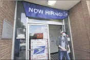  ?? ELAINE THOMPSON — THE ASSOCIATED PRESS FILE ?? On June 4, a customer walks out of a post office branch in Seattle with a banner advertisin­g a job opening.