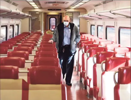  ?? Tyler Sizemore / Hearst Connecticu­t Media ?? A Metro-North conductor collects tickets on the local train between Greenwich and Stamford on Tuesday. New Haven Line ridership is down 80 percent and service has been reduced 38 percent as the railroad awaits crucial federal aid.