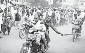  ?? Photograph­s by Ben Curtis
Associated Press ?? IN KANO, a supporter of opposition presidenti­al candidate Muhammadu Buhari prepares to make sparks by scraping a machete on the road during a celebratio­n of Buhari’s anticipate­d victory in the Nigerian election.