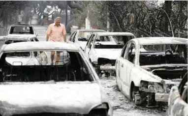  ?? PICTURE: AP ?? CARNAGE: A man passes burnt-out cars in Mati, east of Athens. Gale-fanned wildfires raged through holiday resorts near Greece’s capital, killing an estimated 50 people by yesterday and injuring more than 100, including 11 of whom were in a serious...