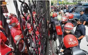  ??  ?? Strong arm of the law: Police personnel trying to control the situation in front of the main gate of the Kuala Lumpur Courts Complex where Umno members were rallying support for Dr Ahmad Zahid.