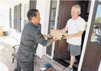  ??  ?? Harvey Vives, left, makes a food delivery for the East End Market to a home in College Park on April 3.