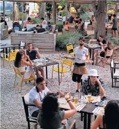 ??  ?? Un camarero sirve las mesas en una pizzería de Palafrugel­l (Girona).