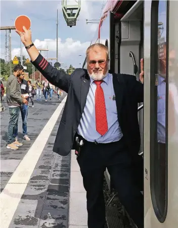  ?? FOTO: JESSICA BALLEER ?? Günter Langen (59) steht mit der Schaffnerk­elle am Bahnhof Wesel und zeigt dem Lokführer an, dass alles bereit ist zur Abfahrt des Regionalex­presses 5 in Richtung Duisburg.