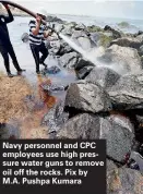  ??  ?? Navy personnel and CPC employees use high pressure water guns to remove oil off the rocks. Pix by M.A. Pushpa Kumara