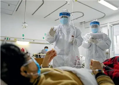  ?? AP ?? Medical workers check on the conditions of patients in Jinyintan Hospital, designated for critical Covid-19 patients, in Wuhan.