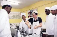  ??  ?? JICA Volunteer Asa Kitawaki teaches students of home economics how to whisk the wet ingredient­s for the Tart au Fruits Frais over the stove.