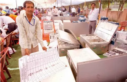  ?? Associated Press ?? A worker rolls up a ballot paper to be pasted outside a booth in Ghaziabad, near Delhi, India, on Wednesday.