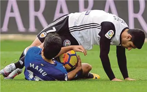  ??  ?? PEMAIN Valencia Goncalo Guedes (kanan) terjatuh selepas diasak pemain Alaves Manuel Alejandro di Stadium Mendizorro­za.