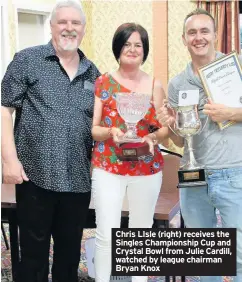  ??  ?? Chris LIsle (right) receives the Singles Championsh­ip Cup and Crystal Bowl from Julie Cardill, watched by league chairman Bryan Knox