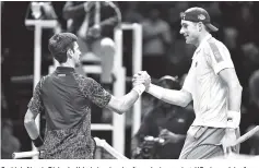  ??  ?? Serbia’s Novak Djokovic (L) shakes hands after winning against US player John Isner during their men’s singles round-robin match on day two of the ATP World Tour Finals tennis tournament at the O2 Arena in London. - AFP photo