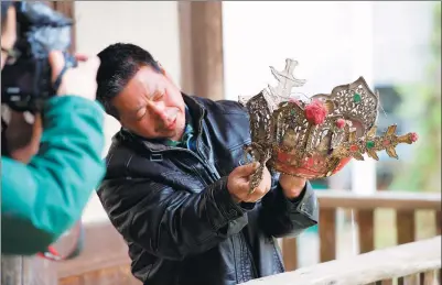  ?? JIANG KEHONG / XINHUA ?? A villager shows off the crown worn by the statue in Yangchun, Fujian province.