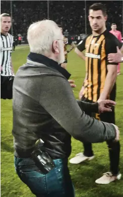  ?? Foto: AFP/Stringer ?? Mit der Waffe im Halfter stürmt Ivan Savvidis, Besitzer von PAOK Saloniki, während des Spiels gegen AEK Athen den Platz.