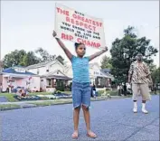  ?? Mark Humphrey Associated Press ?? AKERA PRICE-KING, 9, carries a sign saluting Muhammad Ali in front of the boxer’s boyhood home.