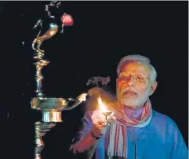  ?? ANI ?? Prime Minister Narendra Modi lights a lamp as a gesture of unity in the fight against Covid-19, at his n residence in New Delhi on Sunday night.