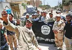  ?? Reuters ?? Members of the Iraqi Army’s 9th Armoured Division are photograph­ed with a Daesh flag, claimed after fighting with terrorists in western Mosul.