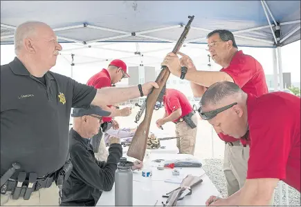  ?? LIPO CHING — STAFF PHOTOGRAPH­ER ?? San Mateo County Sheriff’s Sgt. Pronske, back right, hands a rifle to San Mateo County Sheriff’s Reserve Deputy Simmonds that was turned in at a gun buyback initiated by the Citizens for a San Mateo County Gun Buyback in Redwood City.