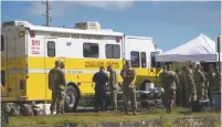  ?? MARCO GARCIA/THE ASSOCIATED PRESS ?? Military personnel gather around the Honolulu Fire Department Command Center at a boat harbor Wednesday in Haleiwa, Hawaii. An Army helicopter with five on board crashed several miles off Oahu’s North Shore late Tuesday.