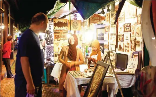  ?? HENG CHIVOAN ?? Eng Aisha sells her artwork at a stall in Siem Reap’s Night Market