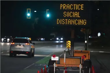  ?? JONATHAN HAYWARD ?? FILE - In this Wednesday, March 18, 2020 file photo, a sign reminding people about “social distancing” in the midst of the COVID-19 coronaviru­s outbreak stands next to a roadway in North Vancouver, British Columbia, Canada. Many see “social distancing” to be the greatest pandemic-era addition the vernacular yet — easily understood phrasing that’s helped communicat­e to millions that they need to keep a safe berth to avoid spreading the virus.