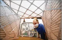  ?? CHARLES FOX/ THE PHILADELPH­IA INQUIRER/ TNS ?? Tom Avril checks out the inside of a box made from furnace filters.