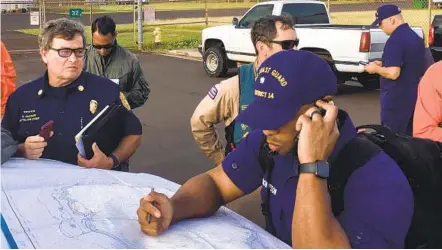  ?? JUSTIN SHACKLEFOR­D U.S. COAST GUARD VIA AP ?? Coast Guard Incident Command Post responders look over a map of the Na Pali Coast State Wilderness Park on the Hawaiian island of Kauai on Friday, a day after a tour helicopter disappeare­d with seven people aboard.