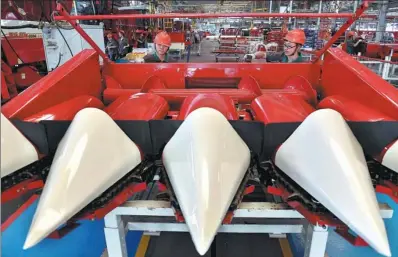  ?? XINHUA ?? Workers operate a cropper at a workshop of Lovol Heavy Industry Co Ltd in Weifang, Shandong province.