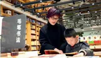  ?? CFP ?? Acompañado de su madre, un chico lee un libro de cultura tradiciona­l china en una librería.
