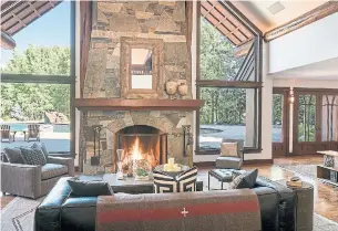  ?? JOSH WELLS PHOTOS SUN VALLEY PHOTO ?? A stone fireplace is flanked by cathedral-style windows that look out onto the pool and woods.
