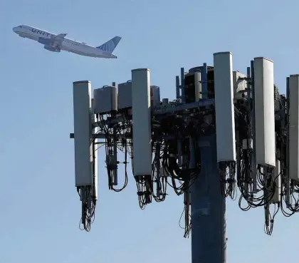  ?? Justin Sullivan / Getty Images ?? A United Airlines plane takes off past a cellular tower Wednesday from San Francisco Internatio­nal Airport. Verizon and AT&T paused rollout of 5G service near airports because the signal could interfere with navigation­al systems.