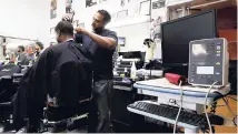  ?? AP ?? Barber Eric Muhammad, owner of A New You Barbershop cuts the hair of customer Marc M. Sims before measuring his blood pressure in Inglewood, California.