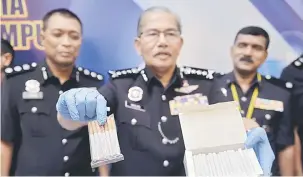  ?? — Gambar Bernama ?? TUMPAS: Mazlan (tengah) menunjukka­n sebahagian 580 batang rokok berisi dadah jenis ganja antara beberapa jenis dadah bernilai RM555,273 yang dirampas dalam satu serbuan di sebuah pusat hiburan di Jalan Sungai Besi, ketika mengadakan pada sidang media di Ibu Pejabat Kontinjen Polis Kuala Lumpur di ibu negara semalam.