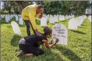 ?? (AP/Miami Herald/Al Diaz) ?? Rachel Moore honors her mother, Patsy Gilreath Moore, as Leroy Lee reaches out to comfort her Wednesday at Simonhoff Park in the Liberty City neighborho­od of Miami. Five hundred coroplast tombstones are being displayed to represent people who have died from the coronaviru­s.