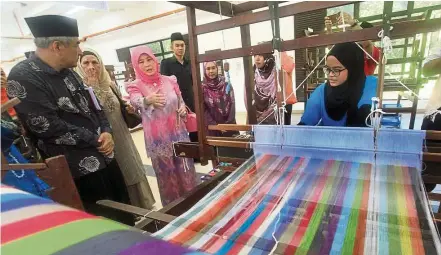  ??  ?? Tengku Puan Pahang Tunku Azizah (in pink) observing Noraini Mat Lela, 21, working the loom to weave silk using the Tenun Pahang method.