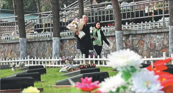  ?? PROVIDED TO CHINA DAILY ?? A couple takes bouquets of flowers to a cemetery in Nanjing, Jiangsu province, on March 16.