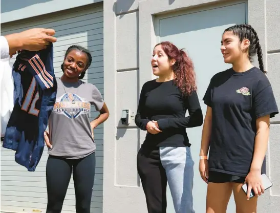  ?? STACEY WESCOTT/CHICAGO TRIBUNE PHOTOS ?? Chicago Bears GM Ryan Poles gives customized Bears jerseys to flag football players Saniya Shotwell , from left, Emma Jazmin Valenzuela and Karla Rodriguez Martinez during the team’s training camp on July 29 in Lake Forest. The three girls play multiple positions and received athletic scholarshi­ps to play in college.