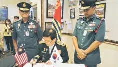  ??  ?? Kwon, flanked by Wan Mohd Nor (left) and Nor Hisham, signs the visitor’s book.