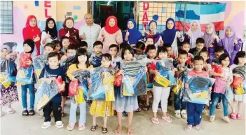  ?? ?? Umno Lahad Datu Division vice-chairman Datin Maizatul Akmam Alawi (centre) with recipients of the school bags and stationery during the “Back to School” programme at Tadika Mutiara Kasih Apartment in Lahad Datu recently.