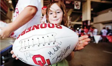  ?? THE OKLAHOMAN] ?? A young OU fan holds out an autographe­d football on Sunday at Meet the Sooners Day in Norman.