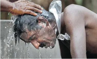  ?? ERANGA JAYAWARDEN­A/THE ASSOCIATED PRESS ?? Kumaradasa, a Sri Lankan farmer suffering from a chronic kidney disease, is helped by his wife in 2013 to bathe in Medavachch­iya. The cause of his disease, which affects from an estimated 70,000 to 400,000 people in Sri Lanka’s rice basket, remains an...
