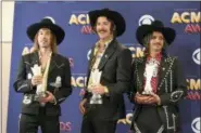  ?? PHOTO BY JORDAN STRAUSS — INVISION — AP ?? Jess Carson, from left, Mark Wystrach and Cameron Duddy, of Midland, pose in the press room with the award for new vocal duo or group of the year at the 53rd annual Academy of Country Music Awards at the MGM Grand Garden Arena on Sunday in Las Vegas.