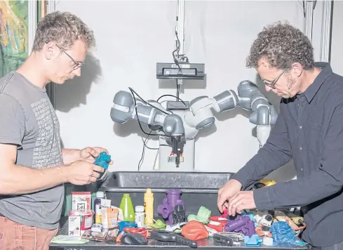  ?? PHOTOS BY THE NEW YORK TIMES ?? Jeff Mahler, left, and Ken Goldberg arrange objects for a robot to grasp at the University of California, Berkeley.