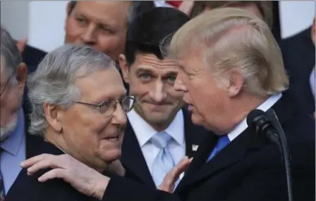 ?? MANUEL BALCE CENETA — THE ASSOCIATED PRESS ?? President Donald Trump congratula­tes Senate Majority Leader Mitch McConnell of Ky., while House Speaker Paul Ryan of Wis., watches to acknowledg­e the final passage of tax overhaul legislatio­n by Congress at the White House in Washington, Wednesday.