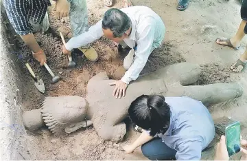  ??  ?? This handout photo taken on July 30 and released on Aug 1 by the Apsara Authority – the state agency charged with managing the Angkor temple complex, shows archaeolog­ists excavating a statue from the ground at the complex in Siem Reap province. — AFP...