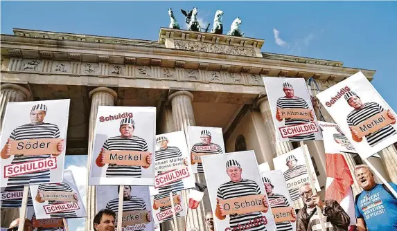  ?? FOTO ČTK/AP ?? Jsou vinni.
Odpůrci roušek a koronaviro­vých opatření se v sobotu sešli v Berlíně před Braniborsk­ou bránou s portréty kancléřky Angely Merkelové a jejích ministrů jako vězňů.