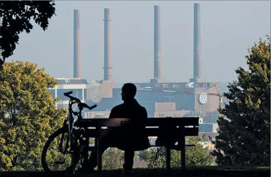  ?? JULIAN STRATENSCH­ULTE / AP ?? Un ciclista descansa en el parque con vistas a la fábrica principal de Volkswagen en Wolfsburgo