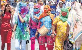  ?? PTI ?? Tourists cover themselves with scarves to avoid the scorching heat during their visit to Heritage Street, near Golden Temple in Amritsar on Saturday.